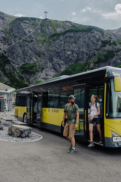 Ein Mann und eine Frau die gerade auf dem Parkplatz vor der Lünerseebahn aus dem Bus aussteigen | © Golm Silvretta Lünersee Tourismus GmbH Bregenz, Philipp Schilcher