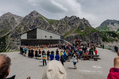 Eine große Gruppe die gemeinsam Alphorn spielt umgeben von einem Publikum | © Golm Silvretta Lünersee Tourismus GmbH Bregenz, Philipp Schilcher